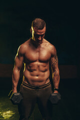 Obraz na płótnie Canvas Man training with dumbbells in the gym