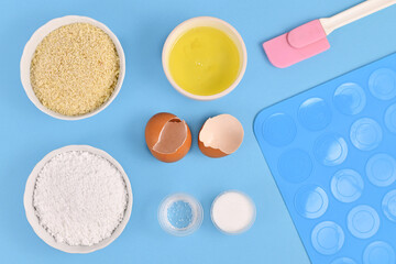Ingredients for making homemade French Macarons sweets including powdered sugar, ground almonds, egg white, salt and baking tools on blue background