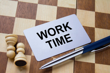 Business card with text Work Time on a chess board with pen and eyeglasses