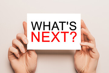 Female hands hold card paper with text what is next on a yellow background. Business and finance concept
