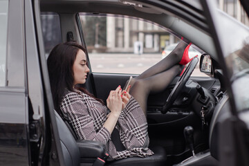 Obraz na płótnie Canvas fabulous Female wearing checkered dress in an automobile with legs in red high-heeled shoes sticking out car window