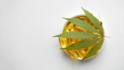 Naklejka na ściany i meble Cannabis CBD capsules are a medical cannabis product with leaves, CBD hemp oil capsules, on white background with copy space