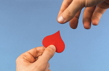 Charity concept, helping hand for world donor day, young boy give a red heart in form of drop, donate