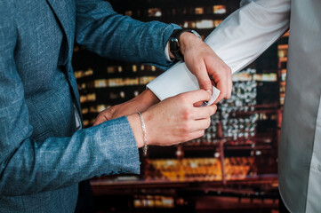 The man fastens the cufflink on the sleeve of his shirt. The groom fastens a button on the sleeve...