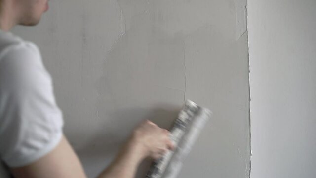 A construction worker builder makes repairs renovation in an apartment or building. Put on a putty, leveling the walls High quality 4k footage