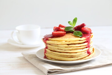 Pancakes with strawberries and mint on a white background