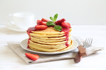 Pancakes with strawberries and mint on a white background