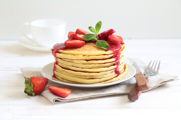 Pancakes with strawberries and mint on a white background