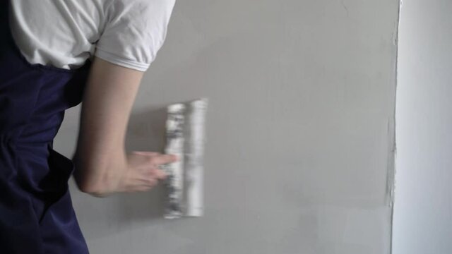 A construction worker builder makes repairs renovation in an apartment or building. Put on a putty, leveling the walls High quality 4k footage