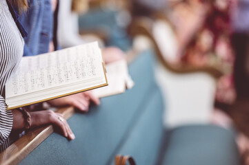 Church choir members holding sheet music and singing during a rehearsal