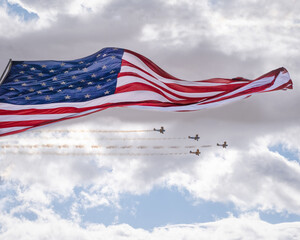 Giant US flag blows in the wind with biplane flyby
