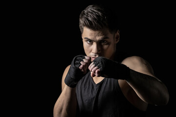 Portrait of young man in boxing wraps posing in boxing stance