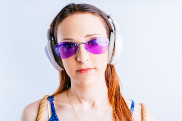 portrait of beautiful young woman on white background wearing summer glasses listening to music with wireless headphones. concept go on vacation
