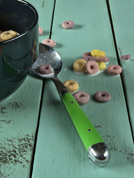 Leche derramada y cereales esparcidos por una mesa de madera verde despu&eacute;s de desayunar.
