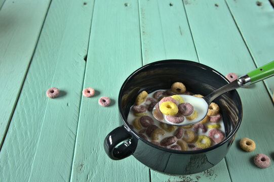 Taz&oacute;n negro con leche y cereales sobre mesa de madera verde claro con copyspace.