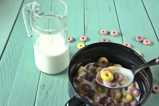 Taz&oacute;n de cereales de colores junto a una jarra de cristal con eche
