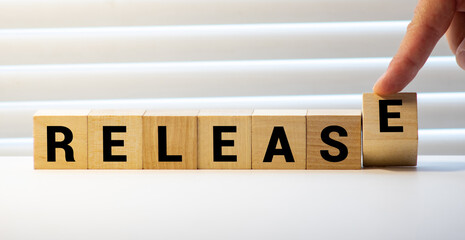 Release message word on a wooden desk on cube blocks with a flower on background.