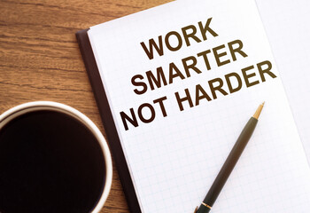 WORK SMARTER NOT HARDER - text on notepad on wooden desk.