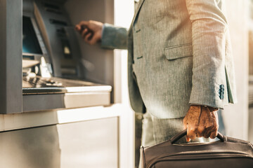 A senior man withdraws money from an automated teller machine (ATM).