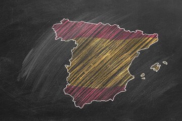 Country map and flag of Spain drawing with chalk on a blackboard. One of a large series of maps and flags of different countries. Education, travel, study abroad concept.
