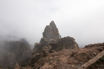 Mountain peak surrounded by mist with the figure of a man at its base