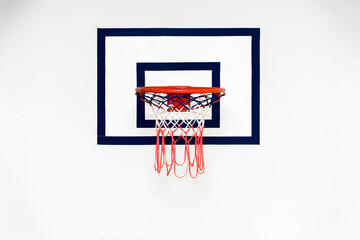 Backboard with red metal basketball hoop hangs on white concrete wall