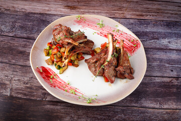 Spicy hot fried spare ribs on a plate against the background of a wooden table.