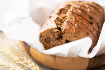 Healthy homemade vegan treats, close up of sliced fresh baked Vegan Banana Bread on the table with wheat grass as a decoration. Copy space, white background, linen table cloth, Morning, Dairy-free.