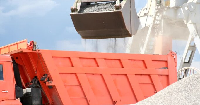 Grab is discharging bulk cargo from a hold of cargo ship, causing dust in atmosphere. Loading in Harbor outdoors. Grapple crane unloading cement clinker from ship to truck in port.  Logistics and Naut