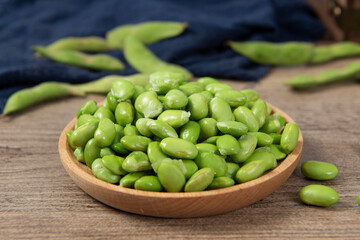 raw green soybean in plate on wooden background. fresh beans.