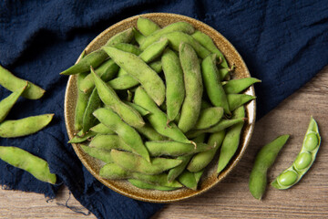 raw green soybean in plate on wooden background. fresh beans.