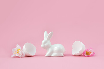 Porcelain figurine of bunny and spring sakura flowers in eggshell. Minimal creative Easter celebration concept. Festive postcard. Selective focus, copy space.