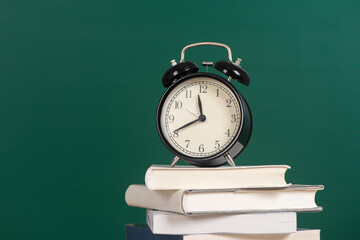 Alarm clock on stack of book with chalkboard  background copy space