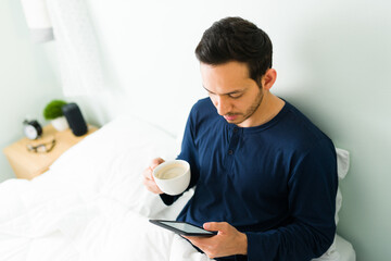 Relaxed man enjoying a digital book in bed