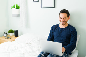 Cheerful man chatting with friends on his laptop