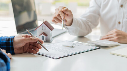 Real estate brokerage contracts for sale and rent with a house on the table in the office.
