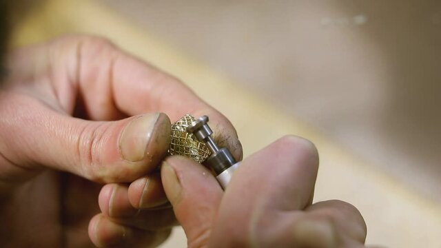 Hand of man creating yellow golden ring , using polishing  machine with a circularly rotating sandpaper or rotary tool . Close up shot . Goldsmith polishes silver or golden ring with polish machine 