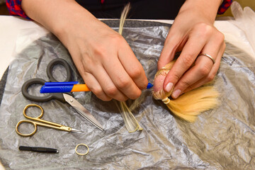 female hands and homemade tool on the table, how to make a hairstyle for a doll, hobby concept