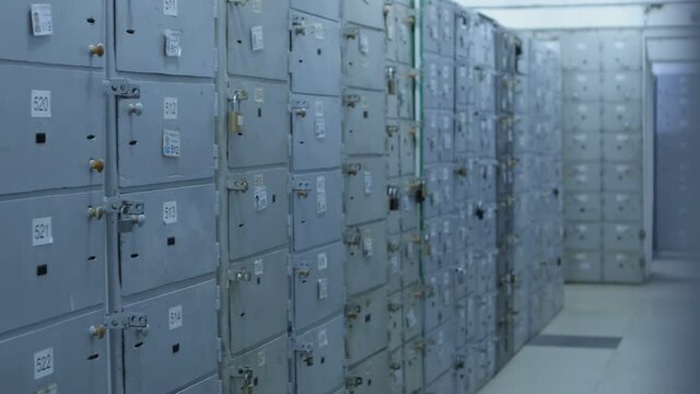 Camera moves along Safe Deposit Boxes in a bank vault room . Security room with many locked cases and numbers  on it . Safe metal Cases with padlock for saving money , jewelry and documents
