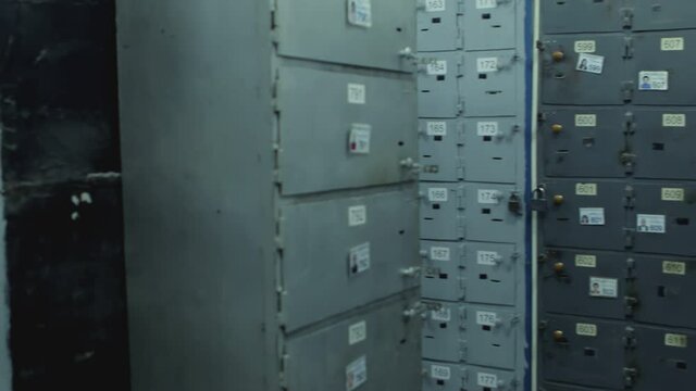 Camera moves along Safe Deposit Boxes in a bank vault room . Security room with many locked cases and numbers  on it . Safe metal Cases with padlock for saving money , jewelry and documents

