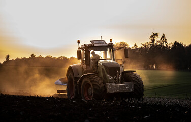 Ploughing a field at sunset with a tractor and plough, ready for crops on a farm