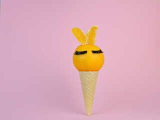 Waffle cone with a ripe tangerine with false lashes and tangerine ears