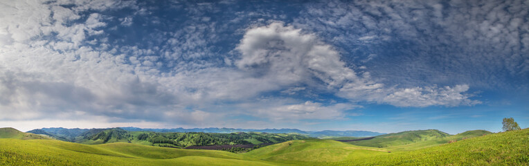 Fototapeta na wymiar Panoramic view of green hills and picturesque blue sky with white clouds
