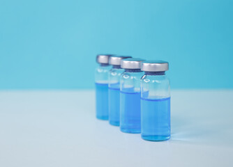 Coronavirus vaccine vials in a row. Medical injection. Medicine vial or flu, measles vaccine bottle with syringe and needle for immunization on medical background. Resistant and prevention disease