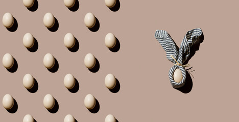 Chicken eggs Pattern and an Egg wrapped in napkin as Easter bunny form on beige background