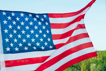 Hanging a American flag on the background of the forest and blue sky