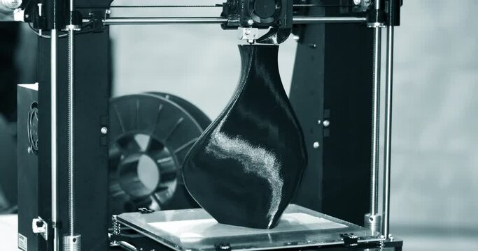 3D printer printing a model in the form of black vase close-up