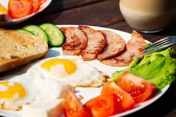 Selective focus on bacon on a breakfast plate. Plate close-up, delicious morning lunch. Toast and fried eggs.
