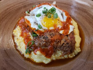 Pulled pork over grits topped with a sunny-side-up egg