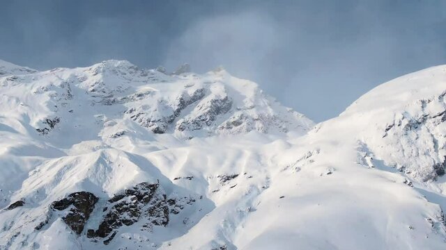 Snow sublimation into vapor on boundless high mountain slopes under sun heat in Elbrus region on sunny spring day aerial motion